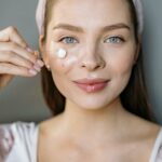 Smiling woman applying facial cream for skincare routine