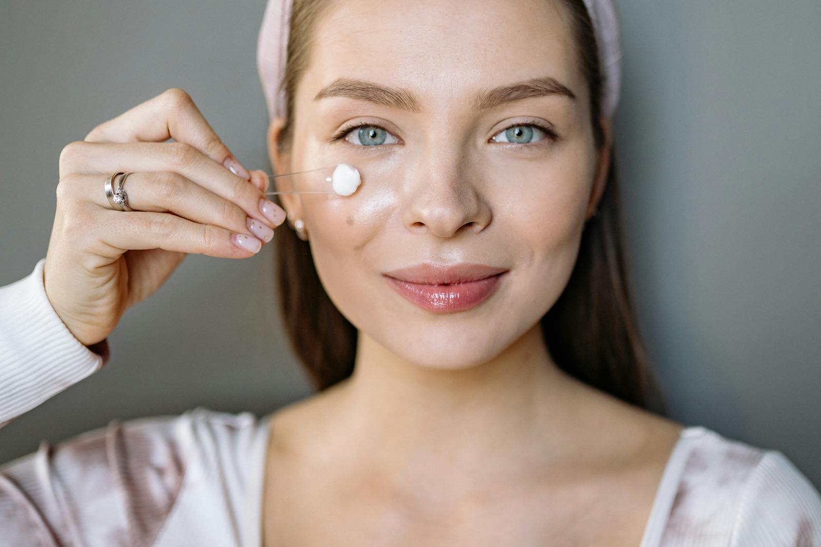 Smiling woman applying facial cream for skincare routine