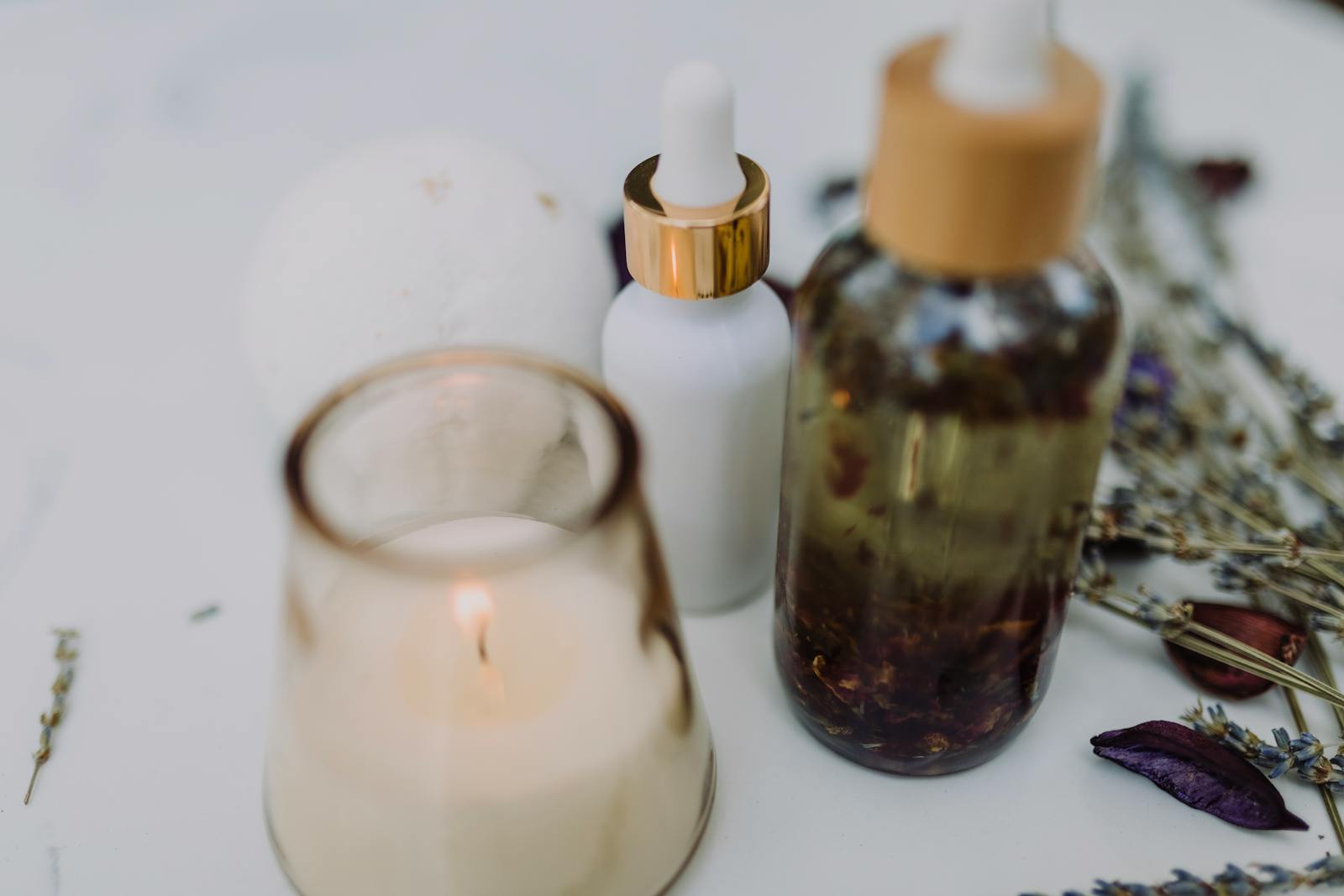 A calming spa setup featuring an aromatherapy candle, essential oils, and dried lavender for relaxation.